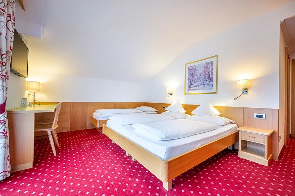Mehrbettzimmer im Garni Crepaz – gemütliche Sitzecke und wohnliche Atmosphäre